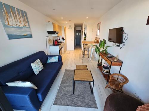 a living room with a blue couch and a kitchen at Studio cabine vue port in Le Grau-du-Roi