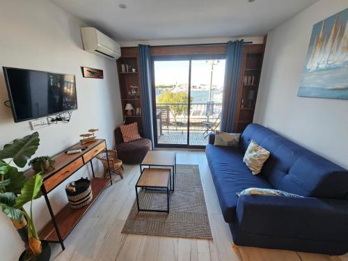 a living room with a blue couch and a tv at Studio cabine vue port in Le Grau-du-Roi
