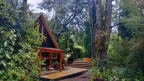a cabin in the woods with a wooden deck at Cabañas bosque sur in Curarrehue