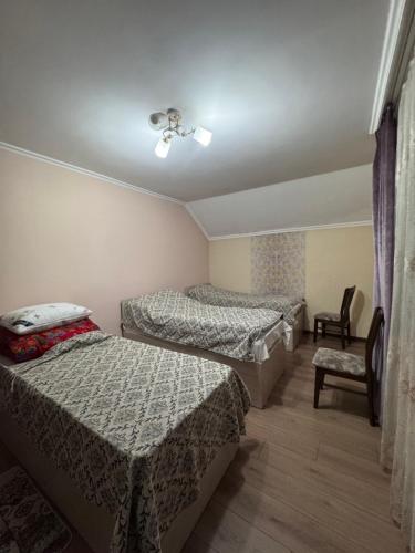 a room with three beds and a chair at Mama Nuris guest house in Karakol