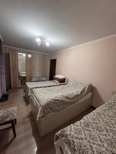 a hotel room with three beds and a chair at Mama Nuris guest house in Karakol