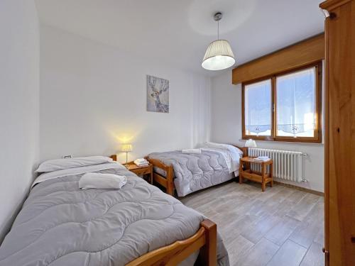 a bedroom with two beds and a window at BBkey La cjase SOT LA STRETE in Arta Terme
