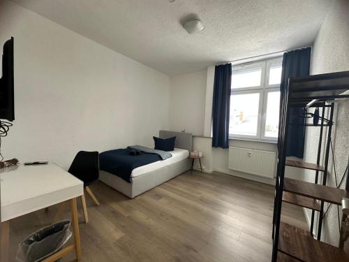 a bedroom with a bed and a desk and a window at Pension BeOne in Trossingen