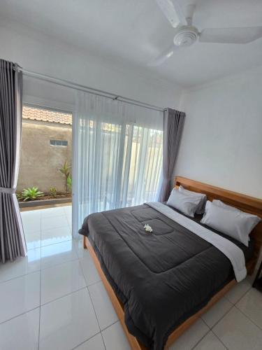 a bedroom with a large bed with a window at Ina Guesthouse in Lovina