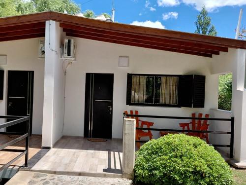 a small house with a porch and two chairs at Cabañas Río in Huerta Grande
