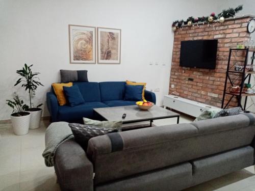 een woonkamer met een blauwe bank en een bakstenen muur bij Sava & Double Rooms in Prijedor