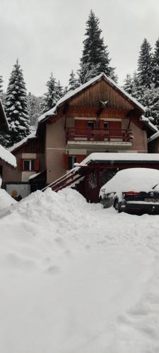 a snow covered house with cars parked in front of it at Vila Miruna in Rausor