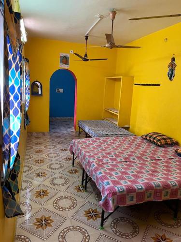 een kamer met een bed en een gele muur bij Temple View Non AC and No Car Parking Guest House Near Kamatchi Amman Temple Guest Check in Time 9PM and Check out 9AM ONLY 12 HOURS in Kanchipuram