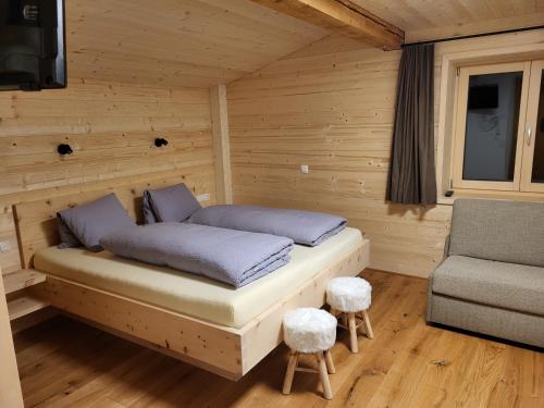 a bed in a wooden room with a chair at Gästehaus Bischof in Damuls