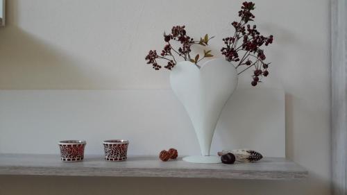 a white vase with flowers in it on a shelf at Ferienwohnung Am Korretsberg in Kruft