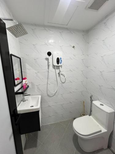 a white bathroom with a toilet and a sink at Alaisya Homestay in Kampung Raja