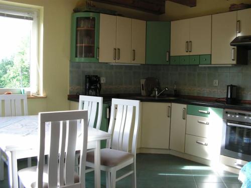 una cucina con sedie bianche, tavolo e piano cottura di Idylla - Cottage in Lower Silesia a Duszniki Zdrój