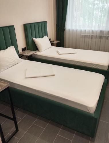two beds with green frames in a room at Berloga Hotel in Pavlodar