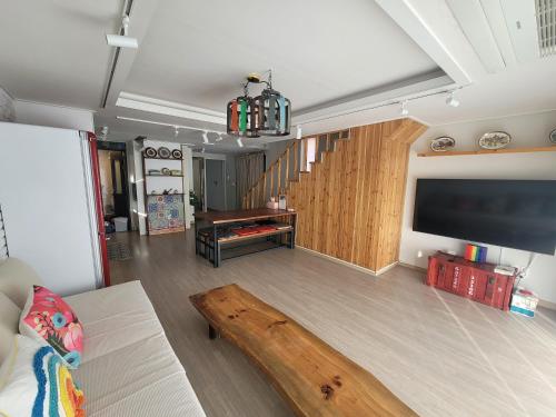 a living room with a couch and a large screen tv at Red Casa in Seogwipo