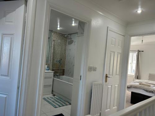 a white bathroom with a shower and a bath tub at Chartsworth 4 Bedrooms Spacious House in Harold Wood
