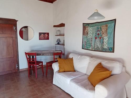een woonkamer met een witte bank en een tafel bij Casa MarJù in Montemassi
