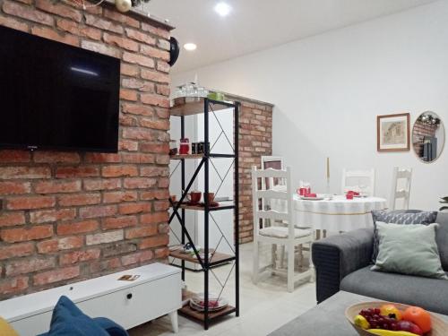 een woonkamer met een bakstenen muur en een tv bij Sava & Double Rooms in Prijedor