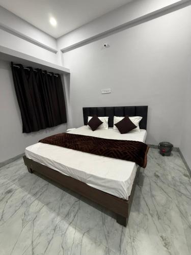 a bedroom with a bed with white sheets and pillows at Hotel Sarkar in Indore