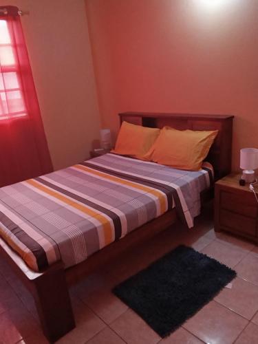 een slaapkamer met een bed met een gestreepte deken bij Cassiane apartments in Thibaud