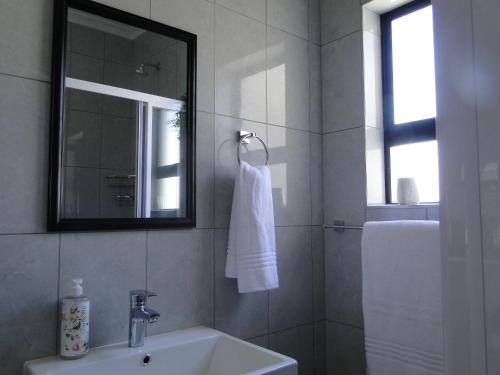 a white bathroom with a sink and a mirror at Fresh Air in Cape Town