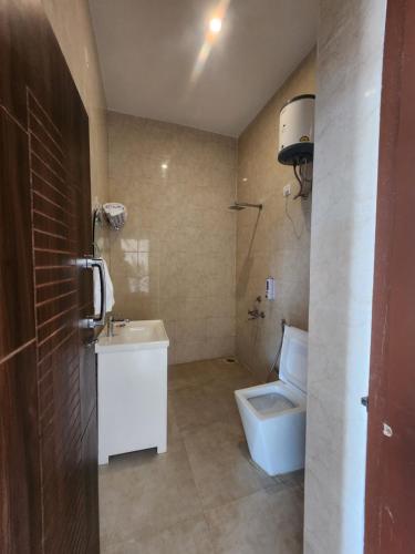 a bathroom with a white toilet and a sink at Himora Bir in Bīr
