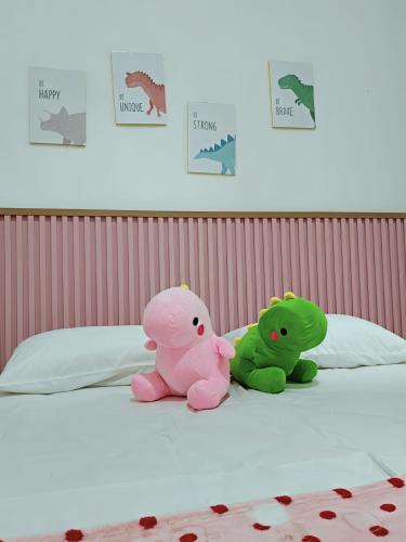 two stuffed animals sitting on top of a bed at Villa Dino Park Batu in Karangploso