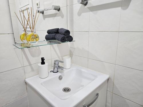 a white bathroom with a sink and towels on a shelf at spacious guest rooms in Lisbon