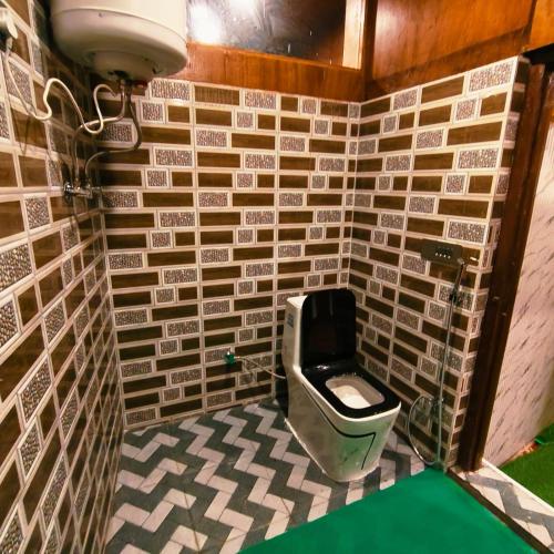 a bathroom with a toilet in a tiled wall at Id villa cottage in Tangmarg