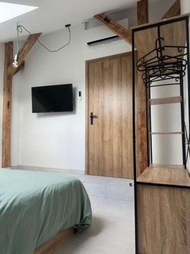 a bedroom with a bed and a tv on a wall at Le gîte de L Échappée Alsacienne in Geispolsheim