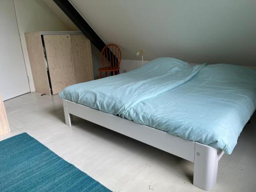 a bed with a blue comforter in a room at De Tuinkamer in Ouddorp