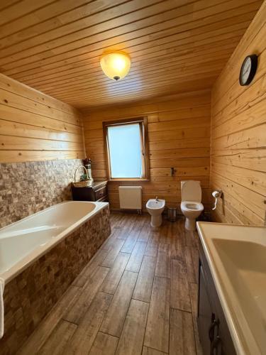 a bathroom with a tub and a toilet and a sink at WOOD house in Skhidnitsa
