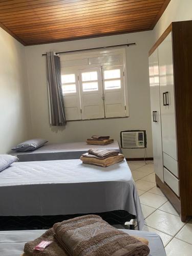 two beds in a room with a window and towels at Apartamento Day in Ilhéus