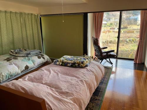 ein Schlafzimmer mit zwei Betten, einem Stuhl und einem Fenster in der Unterkunft Kamida179 in Oguni