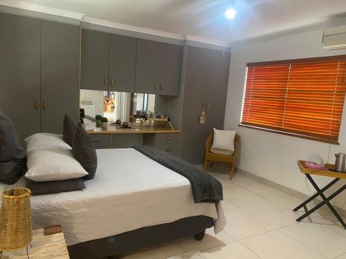 a bedroom with a large bed and a kitchen at The Little Gem in Clanwilliam