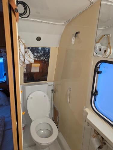 a small bathroom with a toilet in an rv at Wohnwagen mit feststehendem Vorzelt in Fehmarn