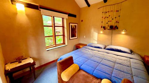 a bedroom with a blue bed and a window at Casa Munay in Urubamba