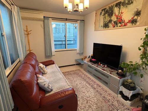 a living room with a leather couch and a flat screen tv at sakuraの家 in Tokyo