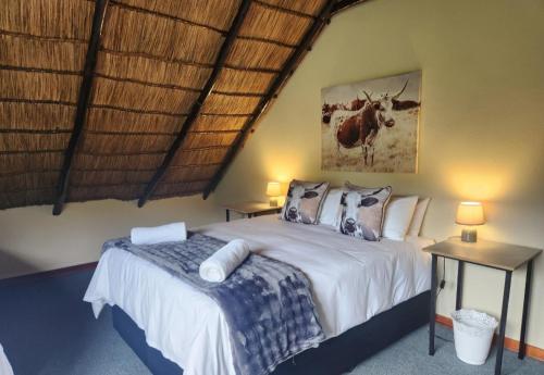 a bedroom with a bed and two tables with lamps at De Kleine Kaap Guesthouse in Lady Grey