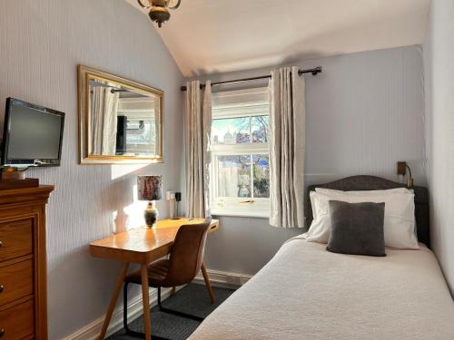 una camera da letto con un letto, una scrivania e una televisione di Greylands Guest House a Llandrindod Wells