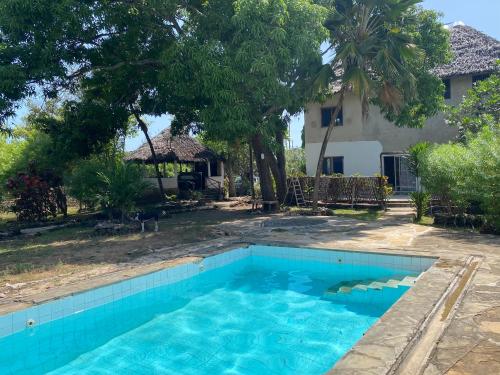 a swimming pool in front of a house at HIGSAM apartment in Diani Beach