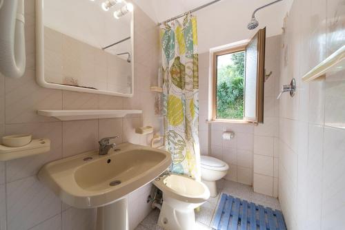 a bathroom with a sink and a toilet and a window at Baia Azzurra in Capoliveri