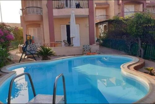 a large blue swimming pool in front of a building at Spacious Villa with Pool and Sea View in Dawwār ‘Abd Allāh