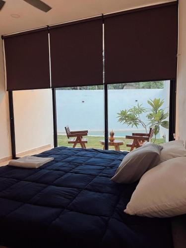 a bedroom with a blue bed with a large window at Muunyal Naj in Valladolid