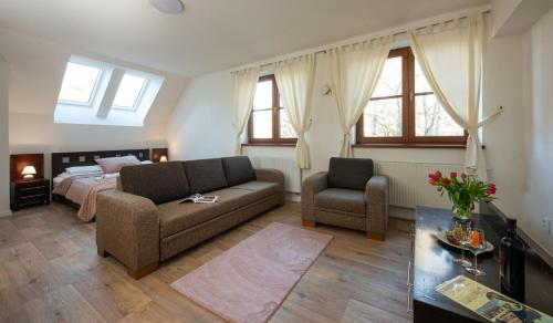 a bedroom with a bed and a couch and a chair at Hotel Tulipan in Tatranská Lomnica