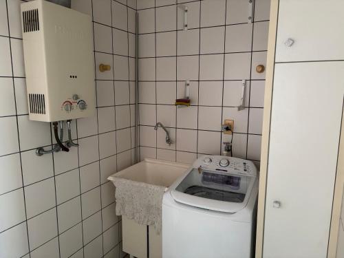 a small bathroom with a washing machine in it at Vista para o molhe in Itapema