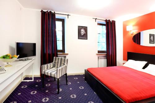 a bedroom with a red bed and a desk with a computer at Hotel Aviator in Nizhnevartovsk