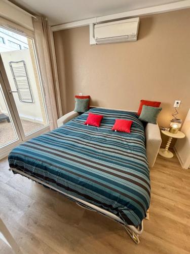 a large bed with red pillows in a bedroom at Studio Cosy et élégant avec Terrasse in Caluire-et-Cuire