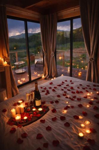 a bed with a bunch of candles and a bottle of wine at Tiny House RosaLodge in Mallemoisson