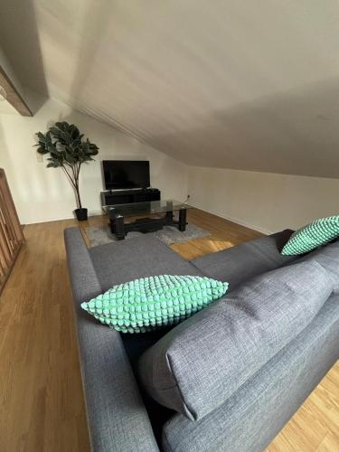 a gray couch with pillows in a living room at Oniris - Parenthèse urbaine in Mont-de-Marsan