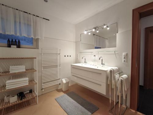 a white bathroom with a sink and a mirror at das Alpenblick & Outdoor Lodge Nauders in Nauders